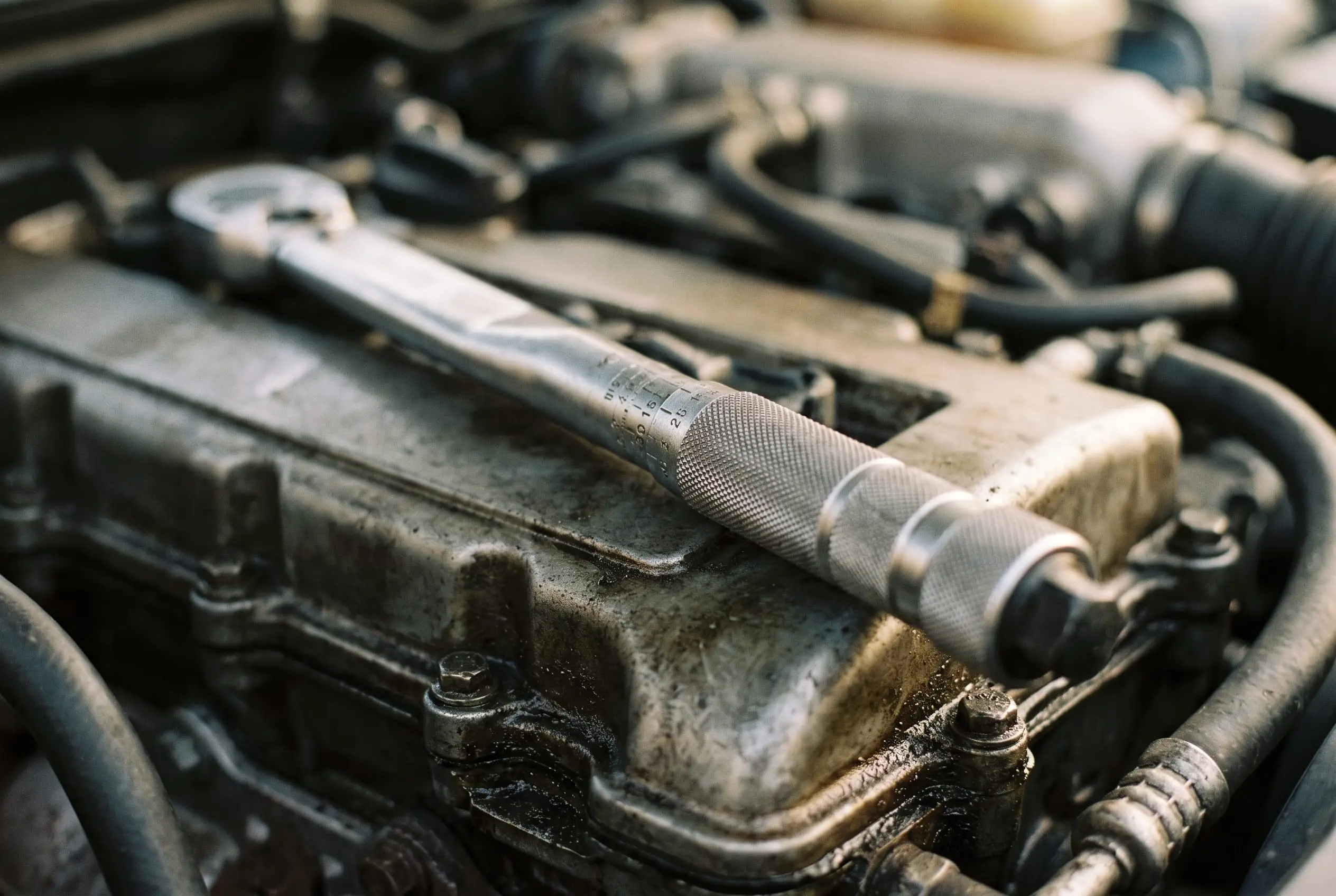 Torque wrench resting on an engine cover under warm workshop light